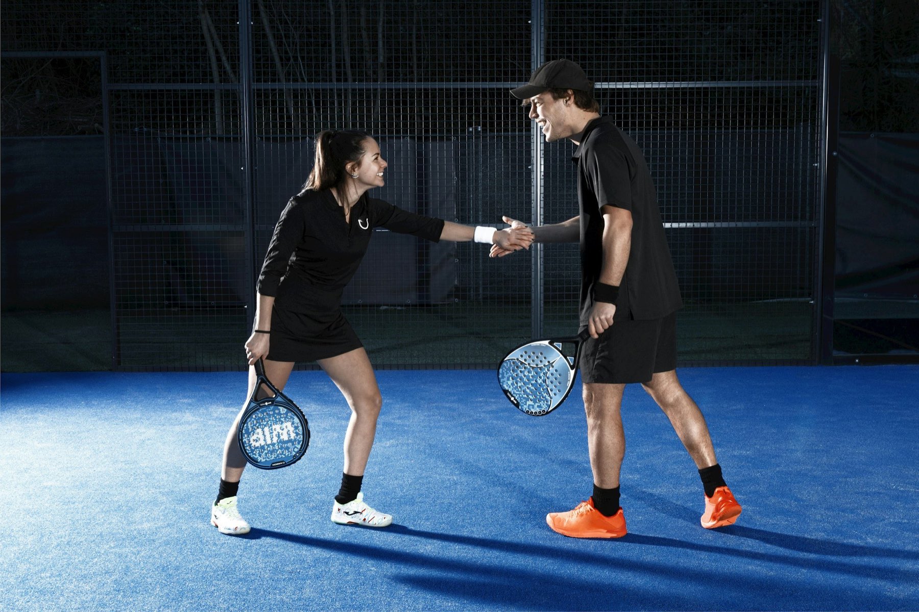 Padelspelers op een verlichte baan in de avond